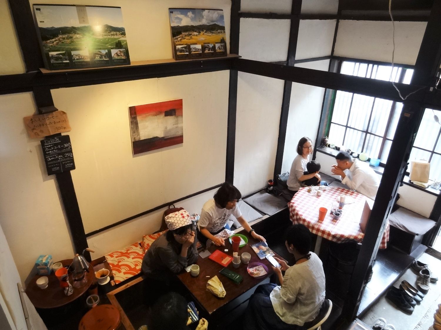 カフェスペースで女性4人が向かい合って座り、テーブルに飲み物やお菓子が置かれ話をする様子を2階から撮影した写真