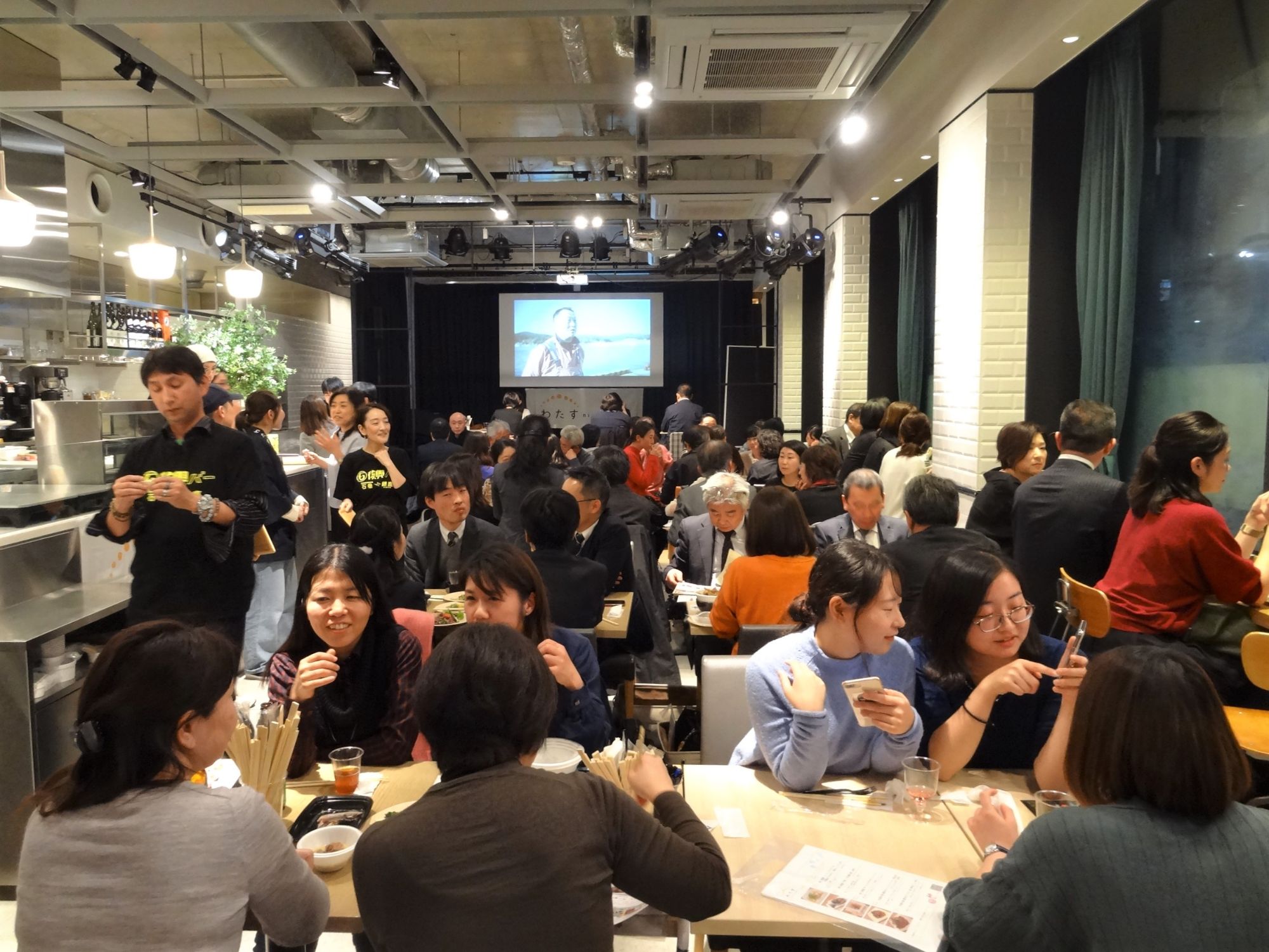 復興バーに来店した大勢の参加者がお酒をたしなみながら、会話に花を咲かせている様子の写真