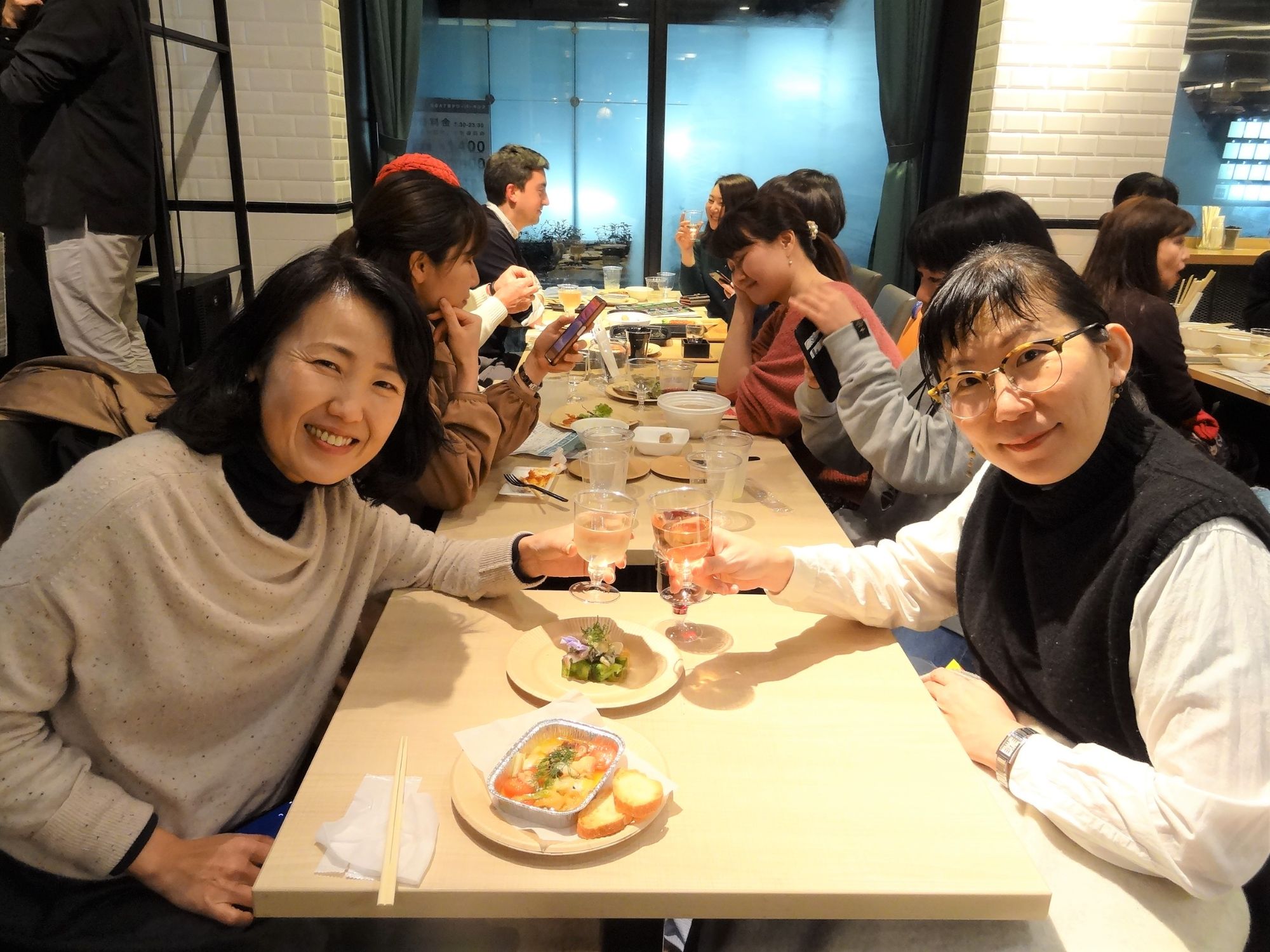 右側に座っているNPO法人「ウィメンズ・アイ」の塩本さんと同席した女性がグラスを持ち、カメラ目線で乾杯を行っている様子の写真