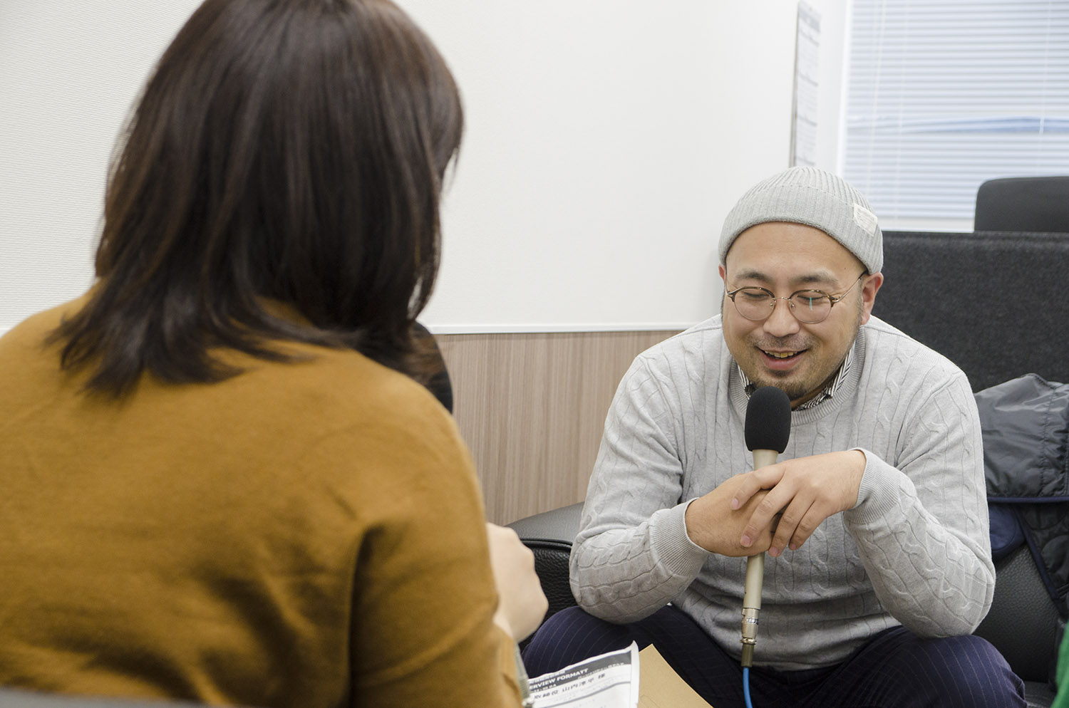 女性リポーターと向かい合って座った山内さんが、マイクを持って笑顔で答えているインタビュー中の様子の写真