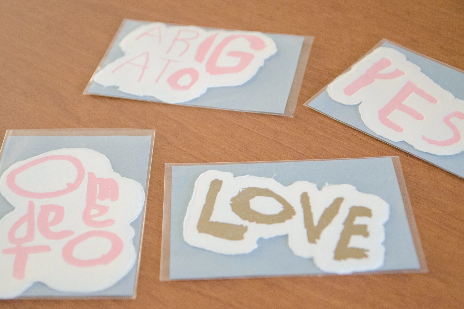 手漉き和紙に「ARIGATO」「YES」「LOVE」「OMEDETO」などの言葉を優しい色合いでデザインされたメッセージカードが並べられている写真