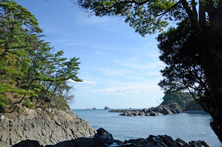 神割崎付近の海岸から見える穏やかな海と、左右に岩場と松の木が立ち並ぶ自然の入り江の風景を日中に撮影した写真