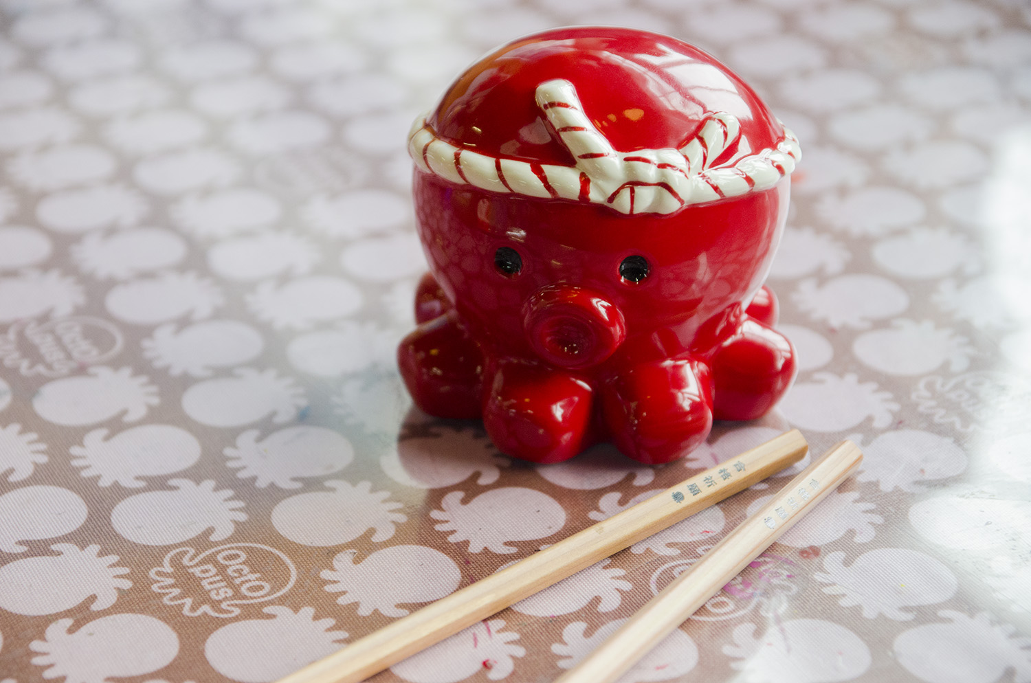 白いねじり鉢巻きを巻いた赤いタコのオクトパス君の陶器の置き物と、2本の鉛筆が並べて置かれている写真