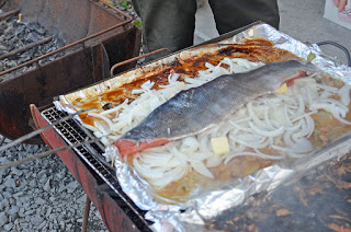 アルミホイルに包んだ玉ねぎの上にサケをのせて屋外の鉄板でバター焼きにしている様子の写真