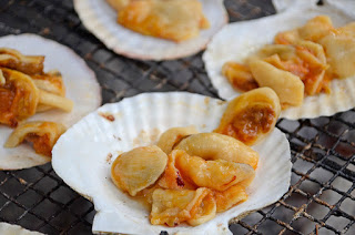 ホタテの貝殻に載せたホタテの身が、炭火の上で香ばしく焼かれている様子の写真