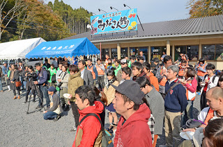 「みなと食堂」の前で、参加者が前方を注視しながら並び、式典やイベントが始まるのを待っている様子の写真