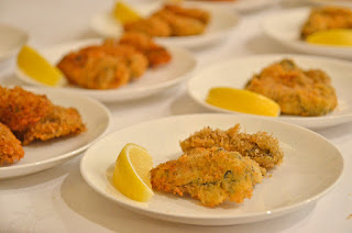 くし切りのレモンが添えられたカキフライ2個が乗った白い小皿が並んでいる写真