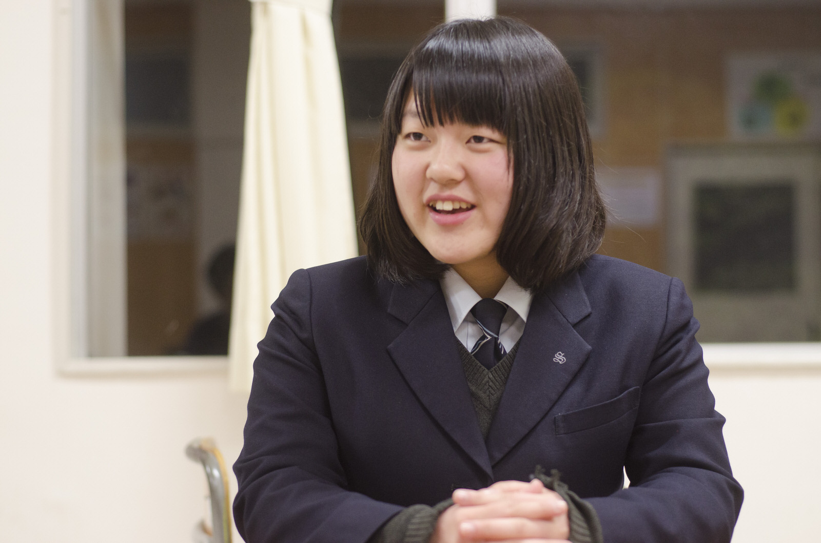 制服姿の大坂さんが教室で座って話をしている写真