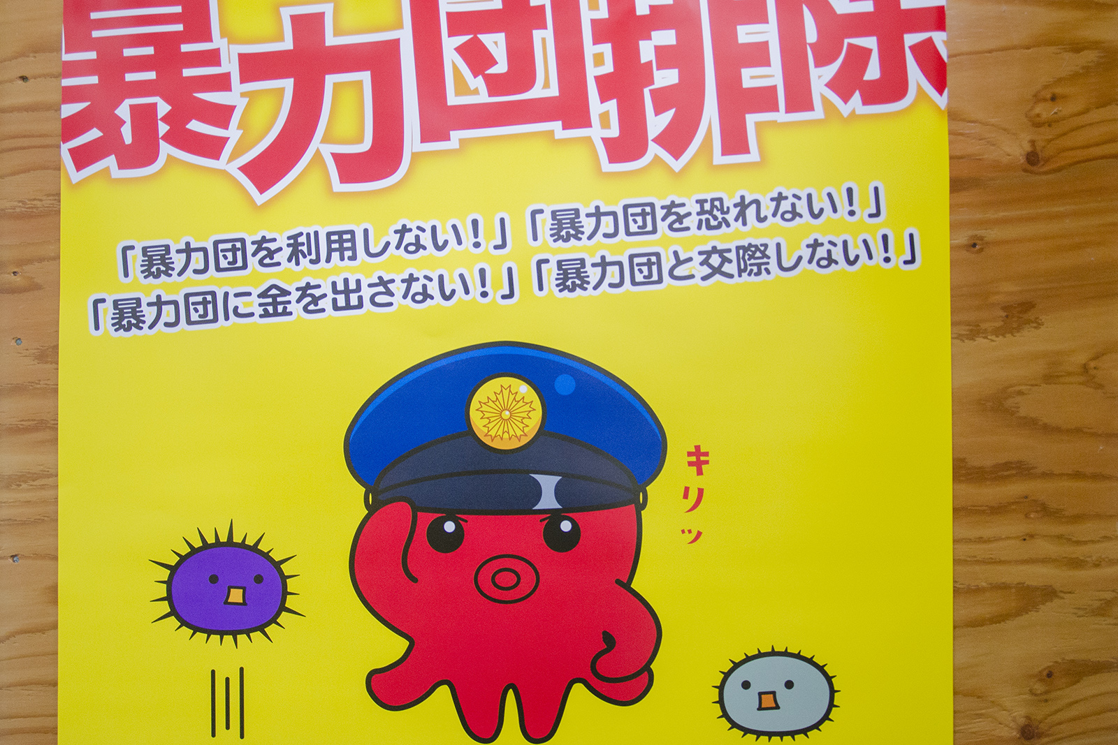 黄色い背景に大きく「暴力団排除」と書かれ、その下に「暴力団を利用しない！」「暴力団を恐れない！」「暴力団に金を出さない！」「暴力団と交際しない！」の文字、オクトポリス君と2つのウニのキャラクターが描かれているチラシの写真