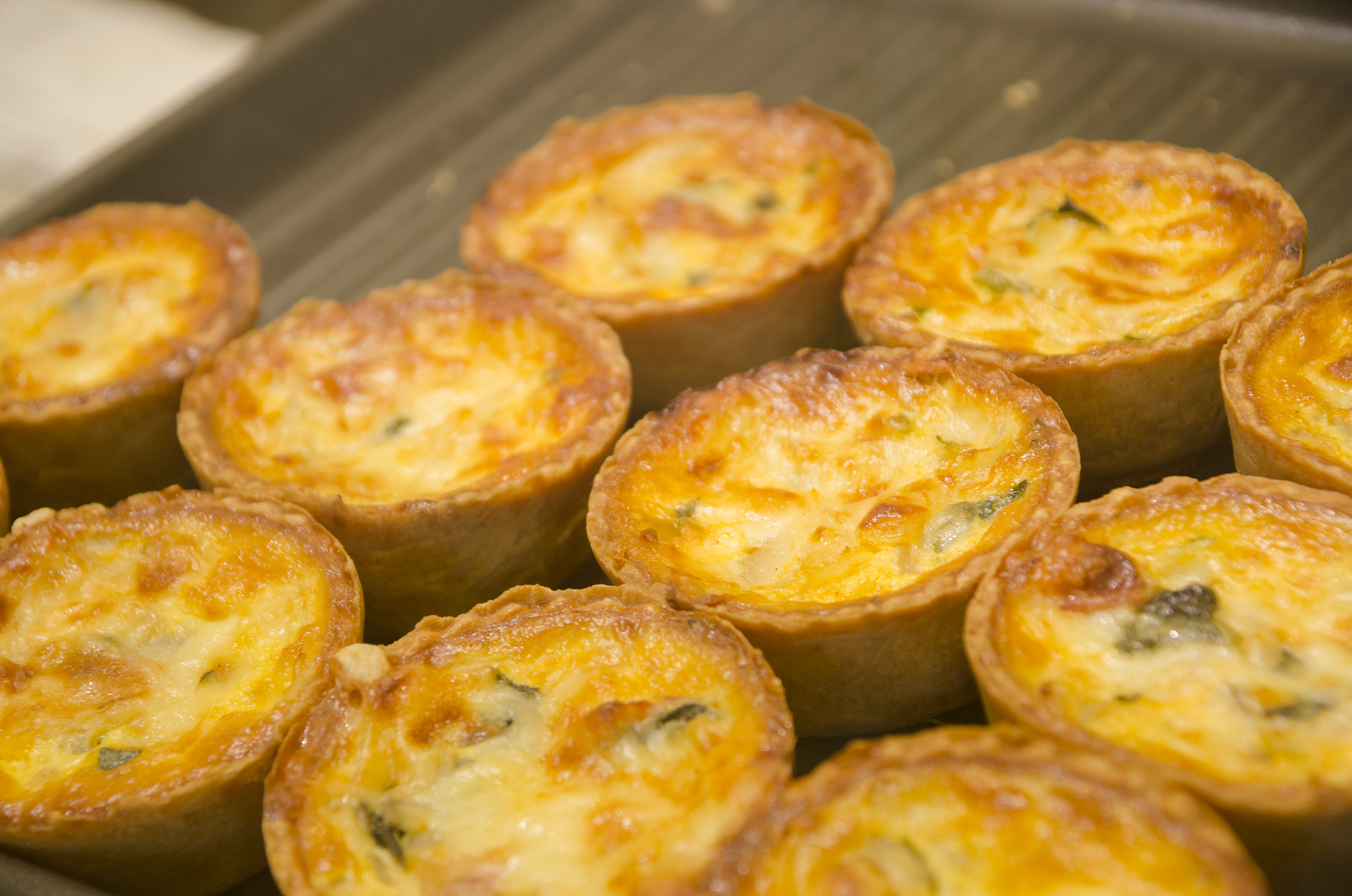 きつね色の焼き目がついた丸い形の「タコプリン」がたくさん並んでいる写真