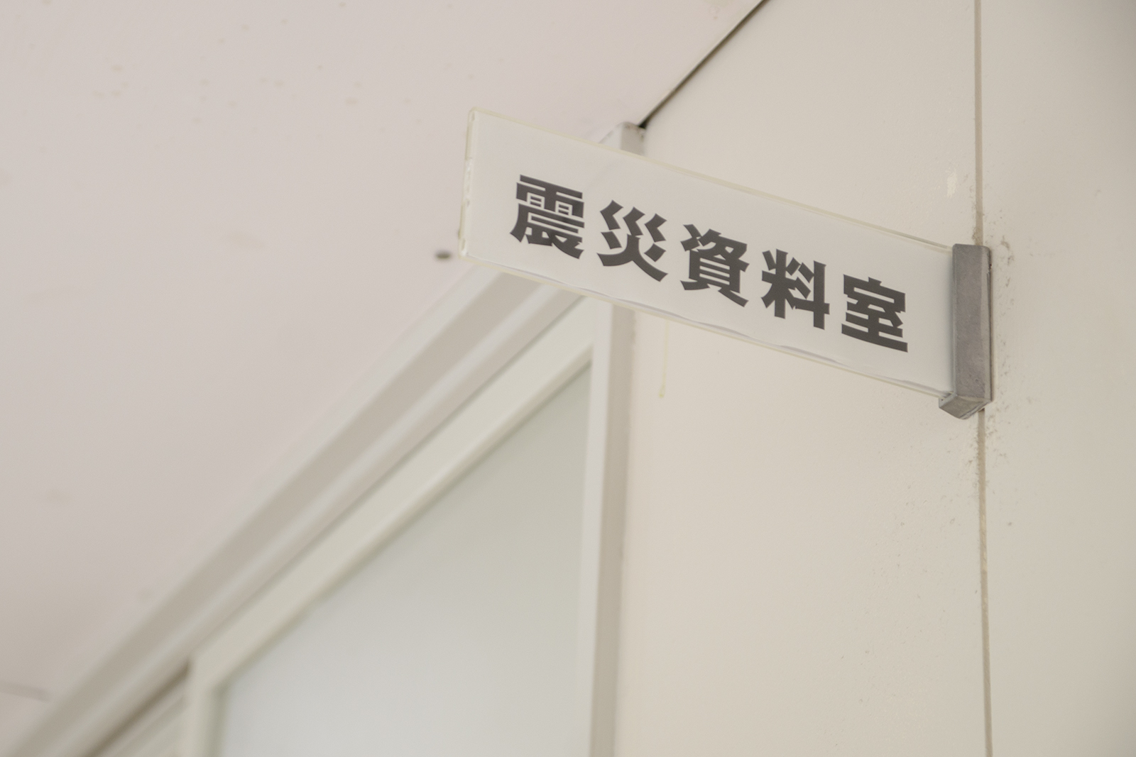 教室の入り口の壁に取り付けられた「震災資料室」と書かれた部屋名表示板の写真