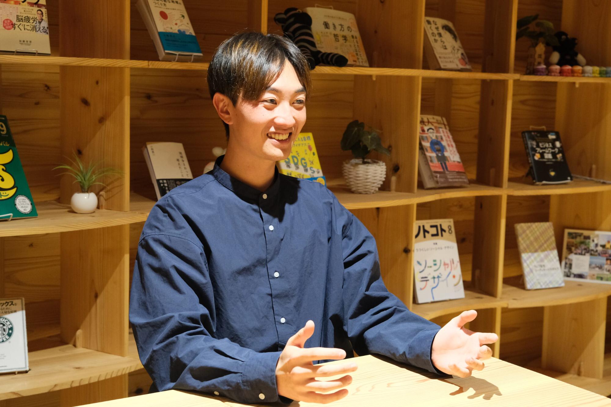 背景には木製の棚があり、笑顔の星空之介さんが手を広げ話をしている写真