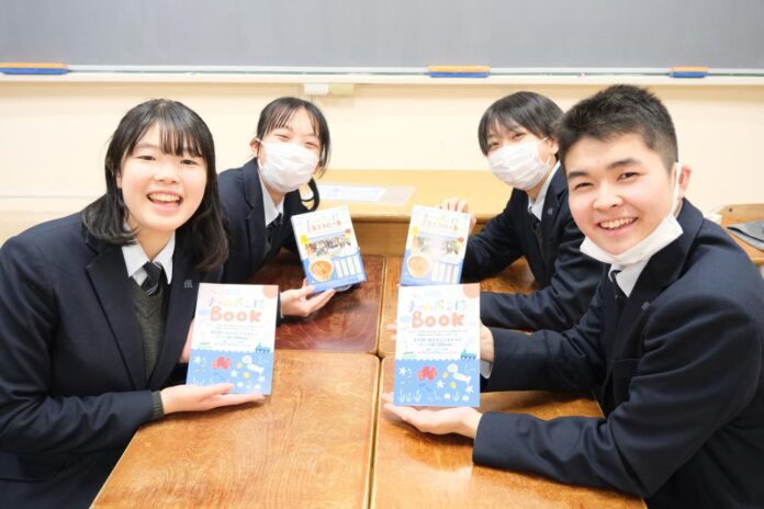 南三陸高校の生徒4人が教室で制服を着て座り、完成した「チーム南三陸BOOK」を手に笑顔で見せている写真