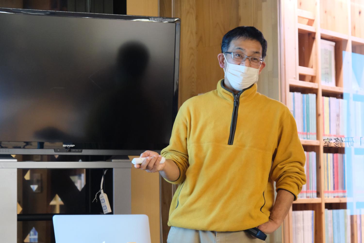 黄色いジャンパー姿の佐藤講師が、テレビ画面や書架の前でリモコンを持ち、参加者へ海鳥の話をしている説明中の写真