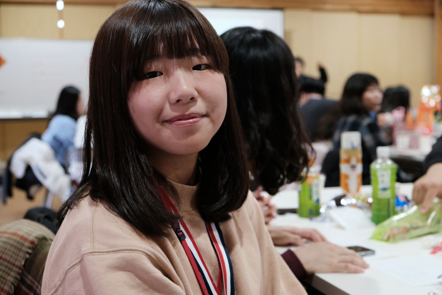 ベージュ色の服を着た台湾の女子大生がカメラに向かって笑顔を見せている様子をアップで撮影した写真