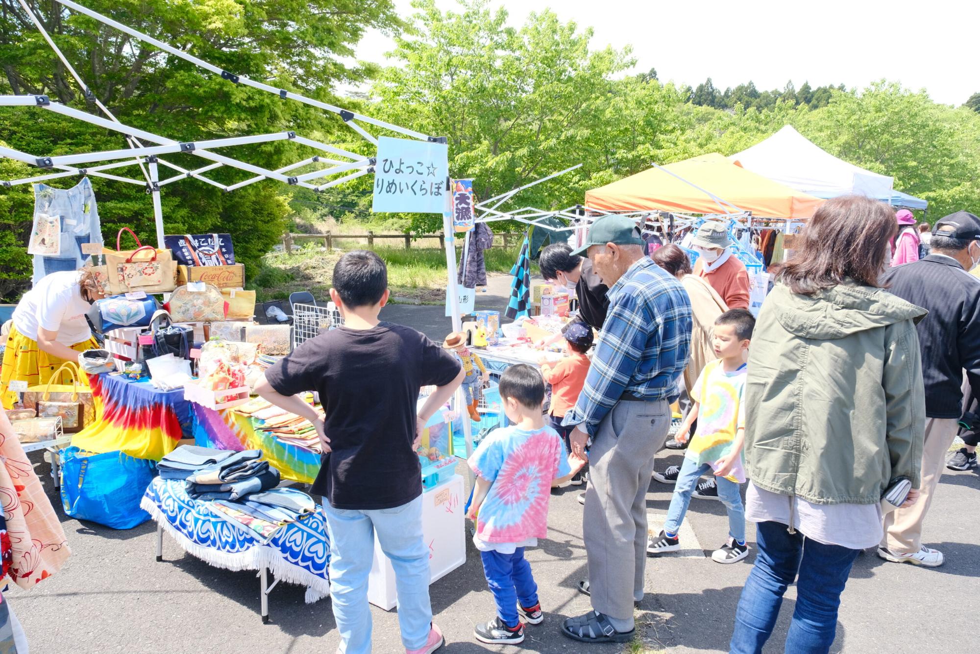 「ひよっこ りめいくらぼ」というカラフルな雑貨が並ぶ店の前に、子どもを連れた恒例の男性が立ち、商品を見ている様子の写真