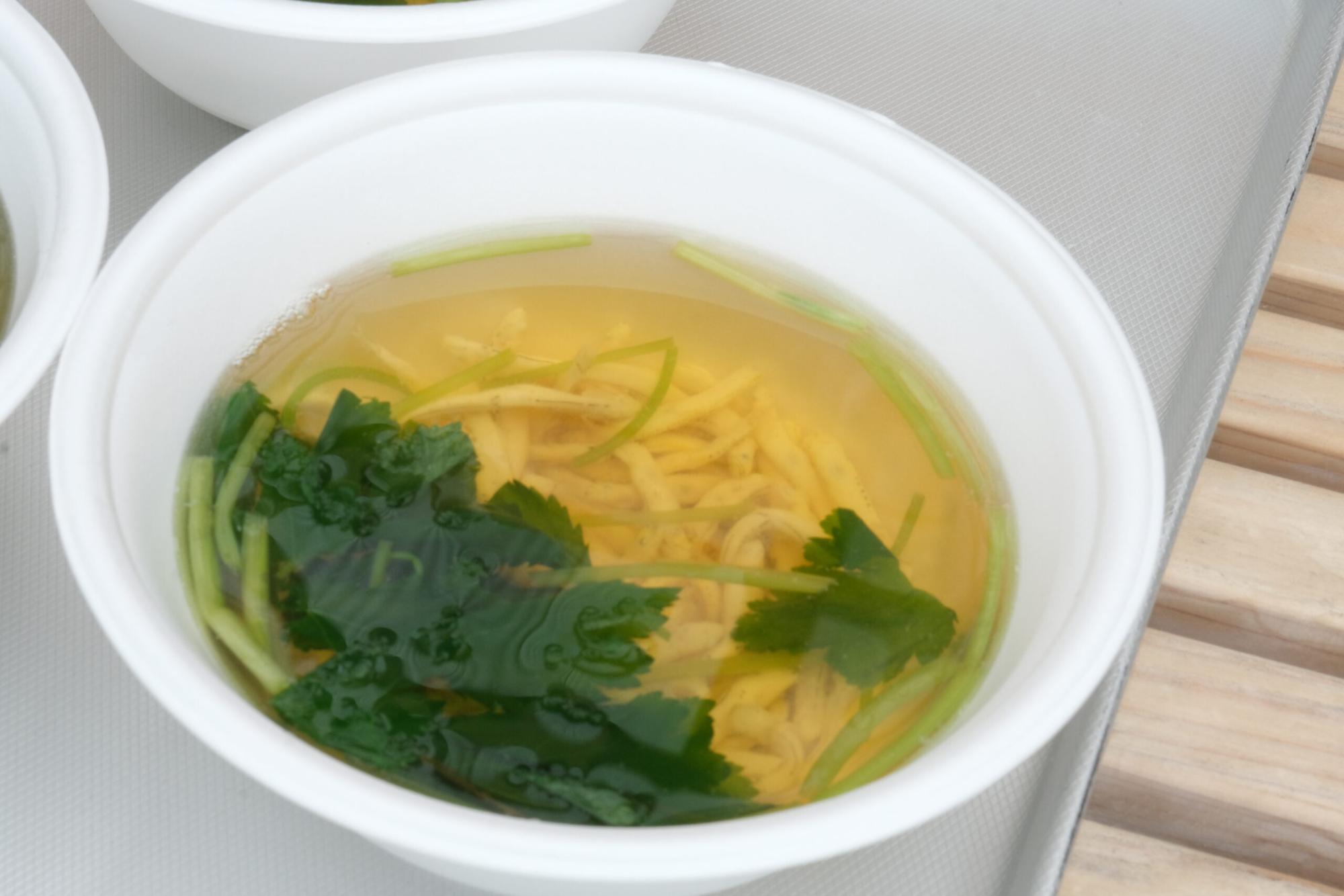 白い使い捨て容器に入った透き通ったスープの中に青菜としらうおの具材が入った吸い物の写真