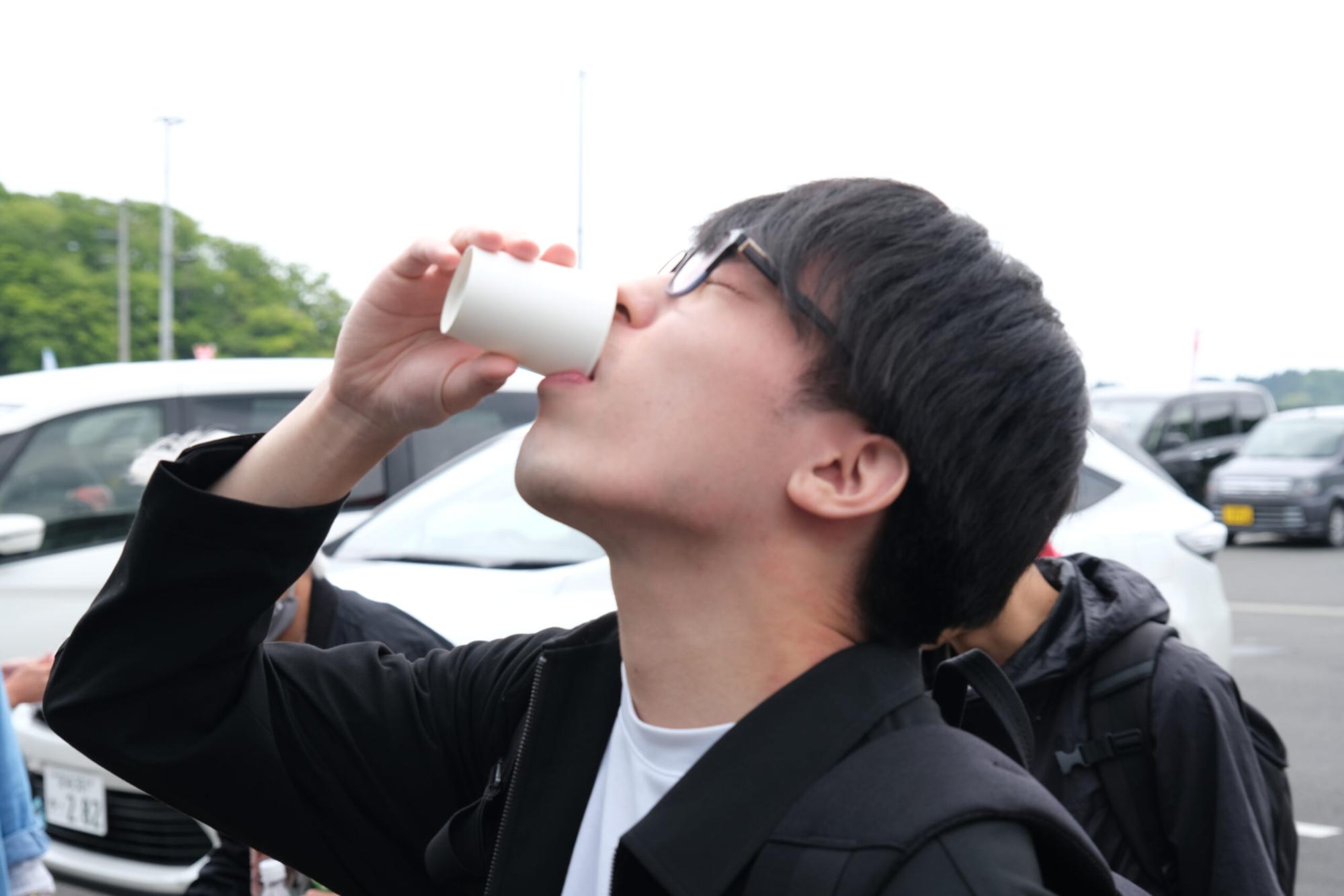 のぶが紙コップに入ったしろうおを飲んでいる様子の写真