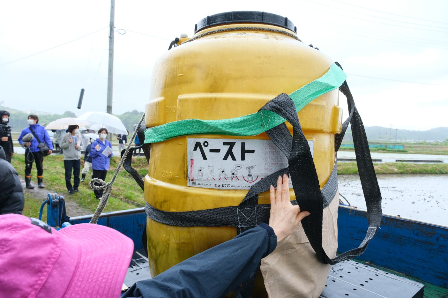 黄色い大きなタンクがトラックの荷台に載っていて、タンクには「ペースト」と書かれたラベルが貼られている写真