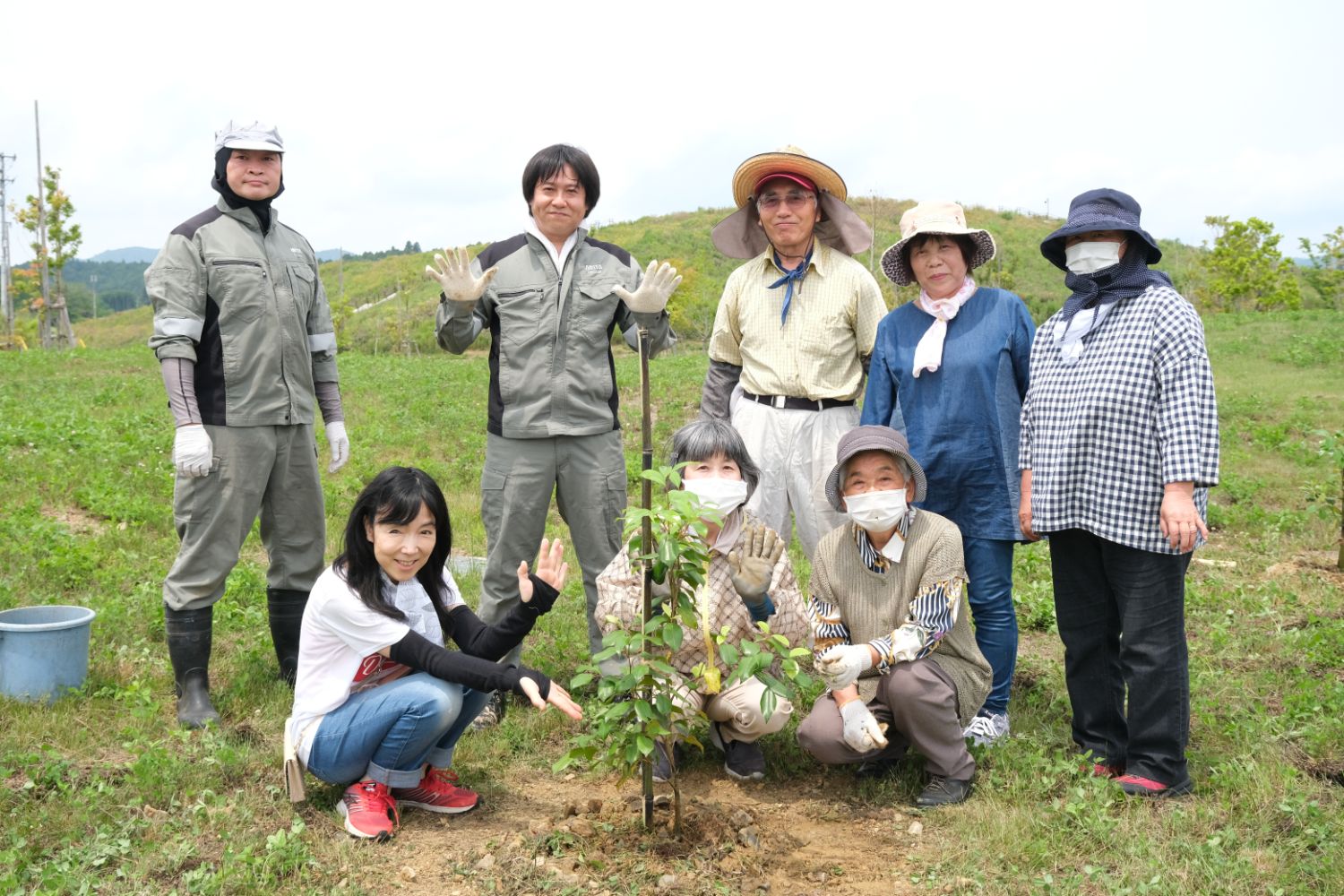 植樹を終えた後、参加者全員が植えた木の周りに集まり、笑顔で記念撮影をしている集合写真