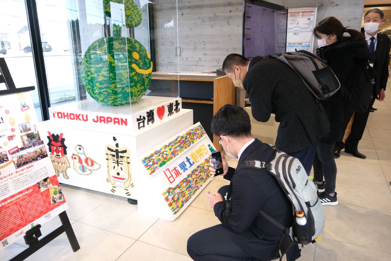 館内展示スペースで、台湾と東北の絆を示すカラフルなブロックアートやパネルを前に、訪問者が写真を撮っている様子の写真