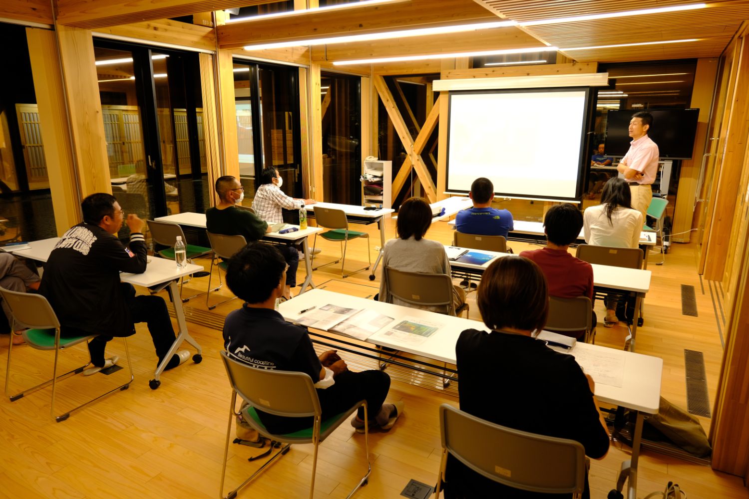 木を多く使った温かみのある室内で、参加者たちが前方のスクリーンを見ながら講師の話に耳を傾けている、ブルーカーボンに関する研修会の様子の写真