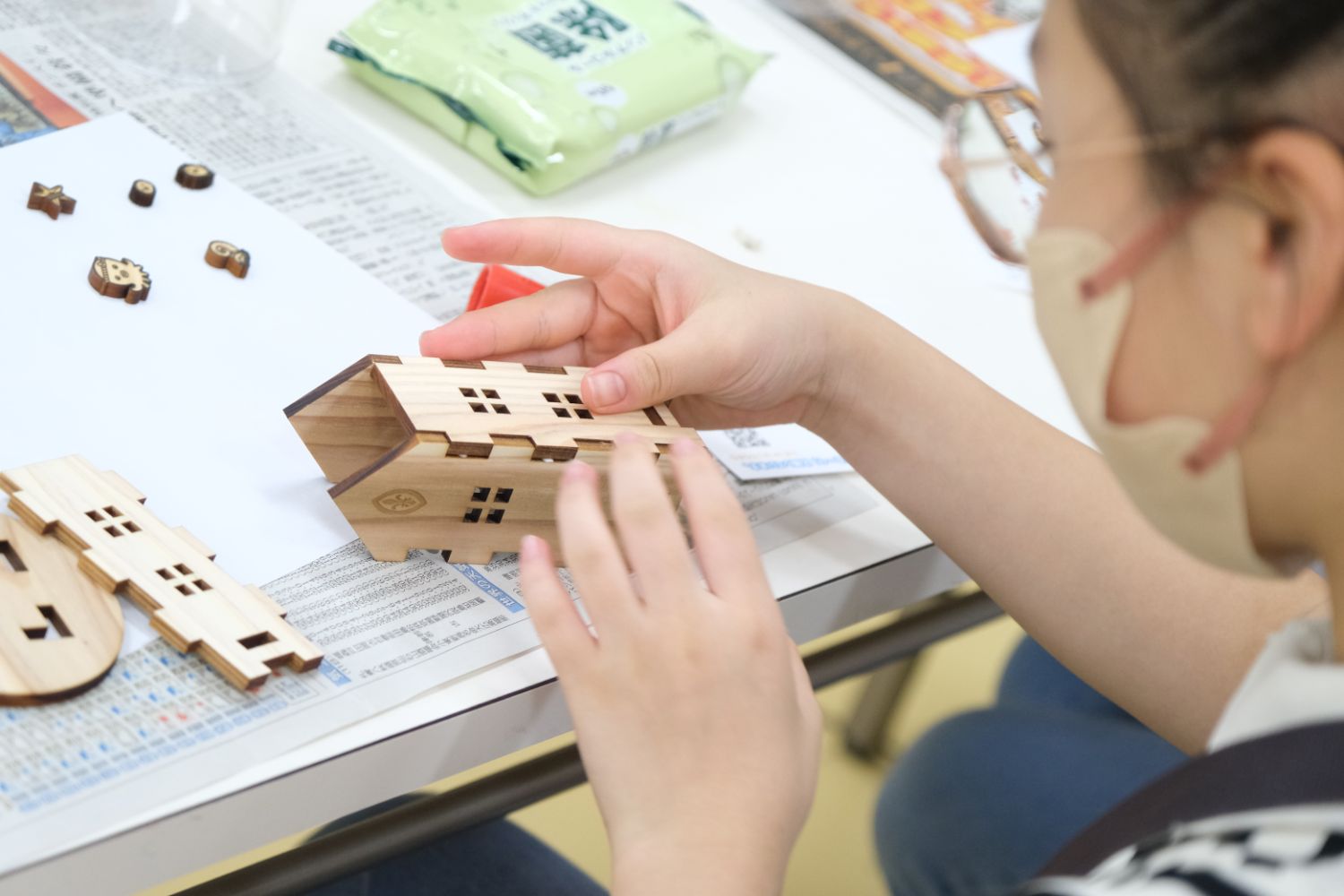 木の家のパーツを組み立てながら、クラフト作業に集中している女の子の写真