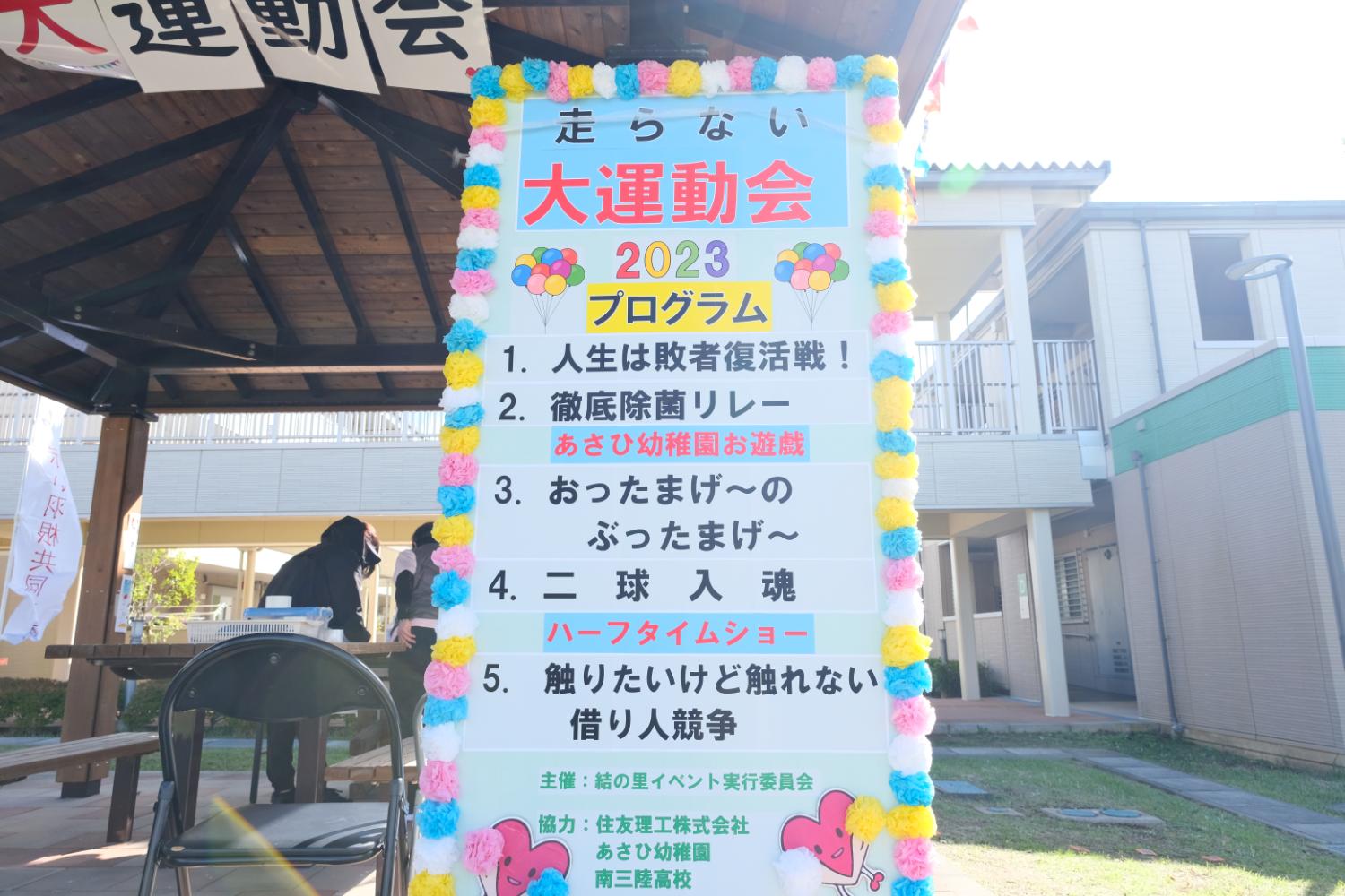 第7回走らない大運動会の競技種目と主催者情報が書かれた華やかなプログラム看板の写真