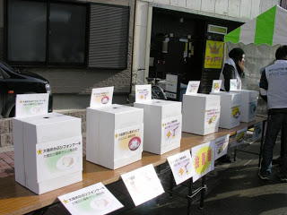 机の上にそれぞれに異なるラベルが貼られた投票箱が並べられている写真