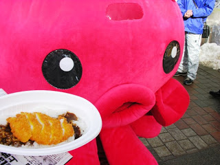オクトパス君が南三陸さんさんタコカレーを持っている写真
