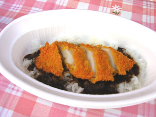 白い楕円形の皿に、デミグラスソースのような濃厚な欧風カレーが盛られ、その上にさくさくのタコカツが載っている復興グルメ南三陸さんさんタコカレーの写真。