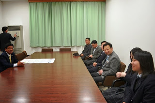 長机に佐藤町長と制服姿の女子学生と関係者の方々が向かい合って座り、談笑している様子を写した写真