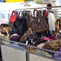 バッグ類が沢山並べられたワゴンと、その背後に立てかけられたハンドバッグの写真