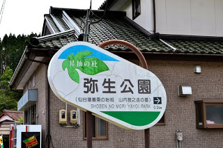 白地に緑の葉の形をした看板に「昇仙の杜 弥生公園」と大きく書かれ、その下に英語で「SHOSEN NO MORI YAYOI PARK」と記されている案内板の写真