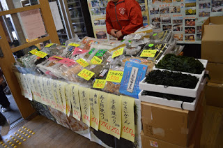 わかめや乾物の商品がテーブルの上に山積みに置かれ、それぞれ上に黄色の値札が置かれている販売ブースの写真