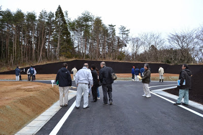 舗装された新しい道路に多くの人が集まり、周囲には土が整えられた宅地が並ぶ完成直後の見学会の写真