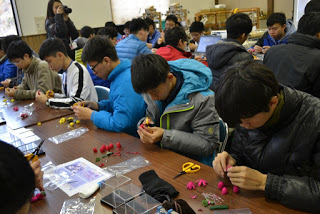 思い思いの色の繭を使って、まゆ細工に真剣に取り組んでいる男子生徒たちの写真