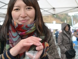 参加者の女性が海苔巻きを両手で持ち、笑顔で写っている写真