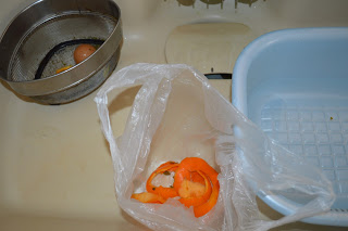 家庭の流し台の中に、ミカンの皮などの生ゴミがビニール袋に入って置かれている写真