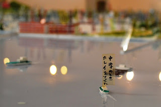 海に浮かぶ小さな船の模型に「中学のときカレイをつってた」と書かれたラベルが立っている近接写真