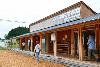 平屋の建物に「恵三郎ポータルセンター」と「Amway House」の看板があり、人々が出入りしている建物の外観を捉えた写真