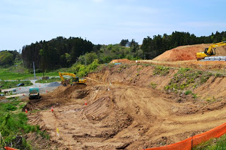 複数の重機で山の斜面を整地している工事現場の写真