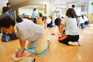 フロアに複数の受講者が膝をついて、各自人形に対して心肺蘇生を練習している様子の写真