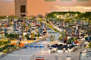 中央に川が流れ、両岸に家々が密集し、その中にたくさんのラベルが立てられている町並みの模型写真