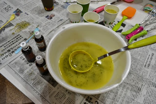 周囲には小瓶や紙コップが並んでいる新聞紙が敷かれた上で、黄色い液体の中に刻んだワカメが浮かんでいるボウルが置かれている写真