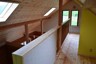 天窓や側面の縦長の窓から自然光が差し込み、2階スペースから吹き抜けを見下ろす構造となっている写真