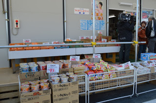 店舗の前に段ボール箱に陳列されたインスタント食品などが並んでいる写真