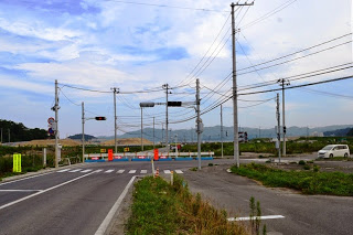 交差点の信号が点滅し、先の道路が仮設フェンスで通行止めとなっている工事中の交差点の写真