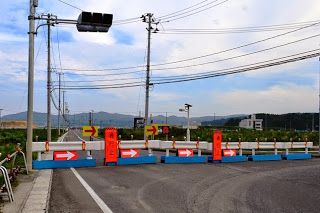 道路が青と白のバリケードおよび赤い矢印看板で完全に封鎖され、右方向に迂回を促している通行止め区間の写真