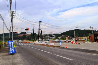 右側に屋根のないガソリンスタンドがあり、手前に「国道45号」と書かれた青い案内看板が立つ信号機のある交差点の写真